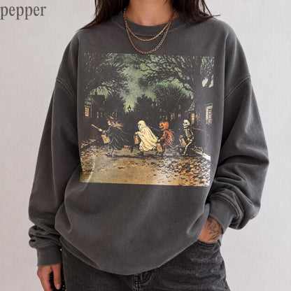 May include: A charcoal gray crewneck sweatshirt featuring a graphic print of four children in Halloween costumes, including a witch, a ghost, a pumpkin, and a skeleton, walking down a tree-lined street at night. The word pepper is visible.