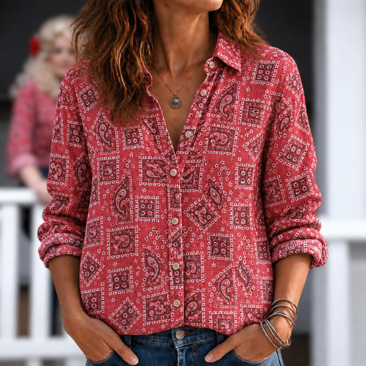 May include: A long-sleeved button-down shirt in a vibrant red hue, featuring a repeating pattern of dark paisley motifs and geometric squares. The shirt has a classic collar, a front button placket, and is paired with blue denim jeans.