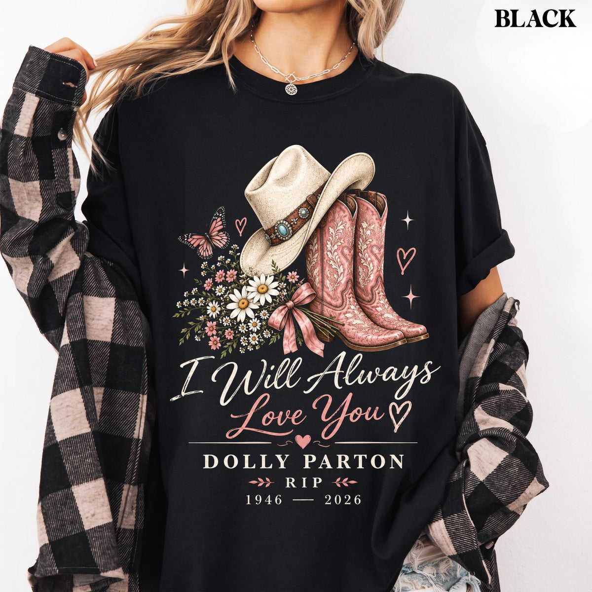 May include: A black t-shirt featuring a graphic of a cowboy hat, pink cowboy boots, a butterfly, and a bouquet of daisies. The text reads: I Will Always Love You, DOLLY PARTON, RIP, 1946-2026. The shirt is worn with a black and white plaid flannel shirt.