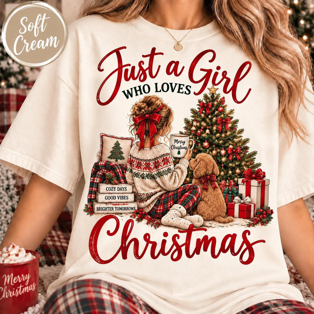 May include: A soft cream t-shirt featuring a graphic of a person with a red hair bow sitting by a Christmas tree with a dog. The text reads Just a Girl WHO LOVES Christmas, with Cozy Days, Good Vibes, Brighter Tomorrows on stacked books.