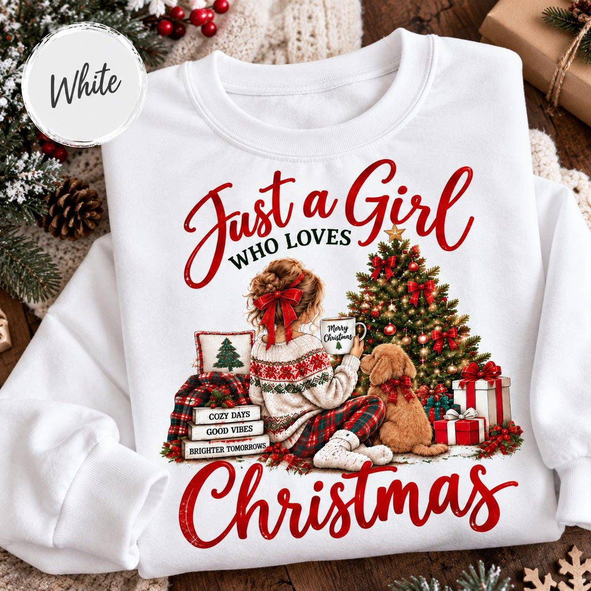 May include: A white long-sleeve sweatshirt featuring a graphic of a person with a red hair bow sitting by a decorated Christmas tree with a dog. The text reads Just a Girl WHO LOVES Christmas, with stacked books labeled Cozy Days, Good Vibes, Brighter Tomorrows.