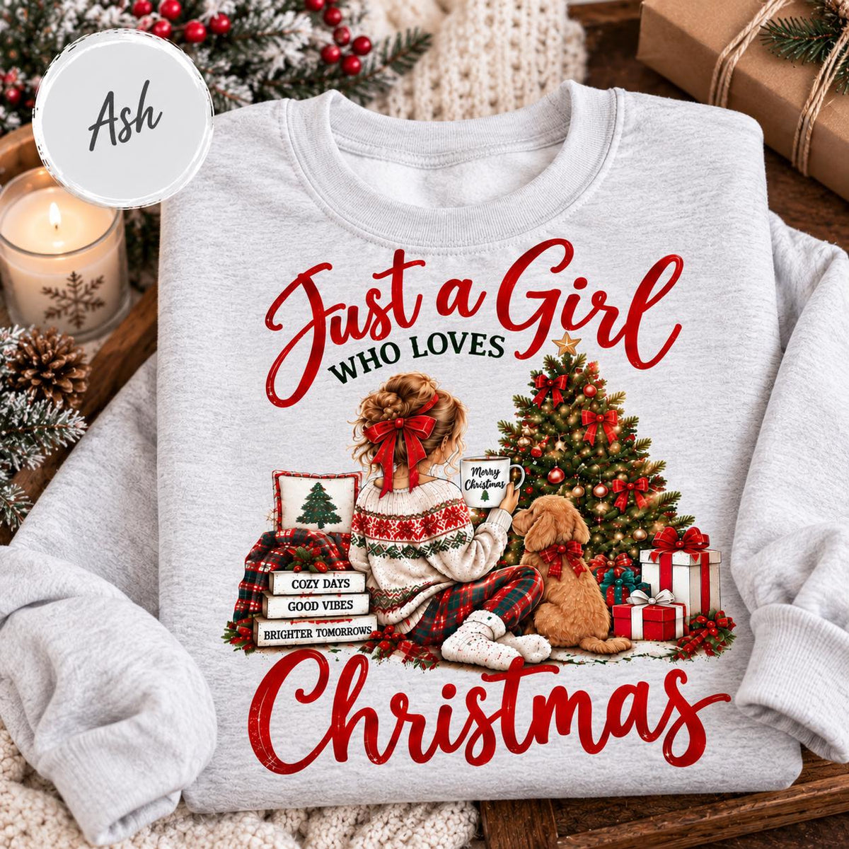 May include: An ash gray crewneck sweatshirt featuring a graphic of a person with a red hair bow sitting by a Christmas tree and a golden dog. The text reads Just a Girl WHO LOVES Christmas, Merry Christmas, COZY DAYS, GOOD VIBES, BRIGHTER TOMORROWS.