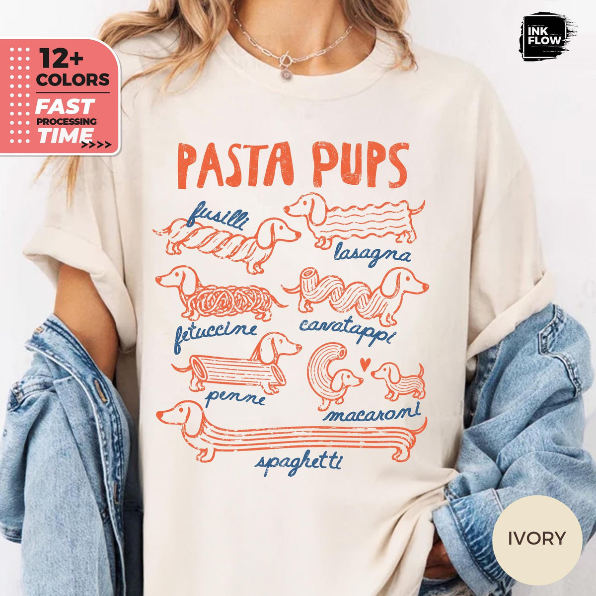 May include: An ivory t-shirt featuring a graphic print titled PASTA PUPS in orange text. The design displays seven dachshund dogs illustrated as various pasta shapes, including fusilli, lasagna, fettuccine, cavatappi, penne, macaroni, and spaghetti.