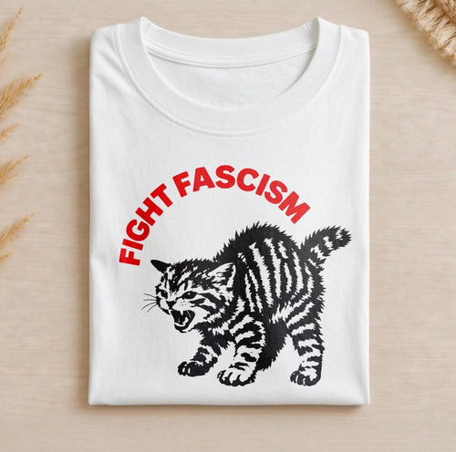 May include: A white crew neck t-shirt featuring a black graphic of a hissing, striped kitten. Above the kitten, the text "FIGHT FASCISM" is printed in bold, red, capital letters. The design is centered on the front of the folded garment.