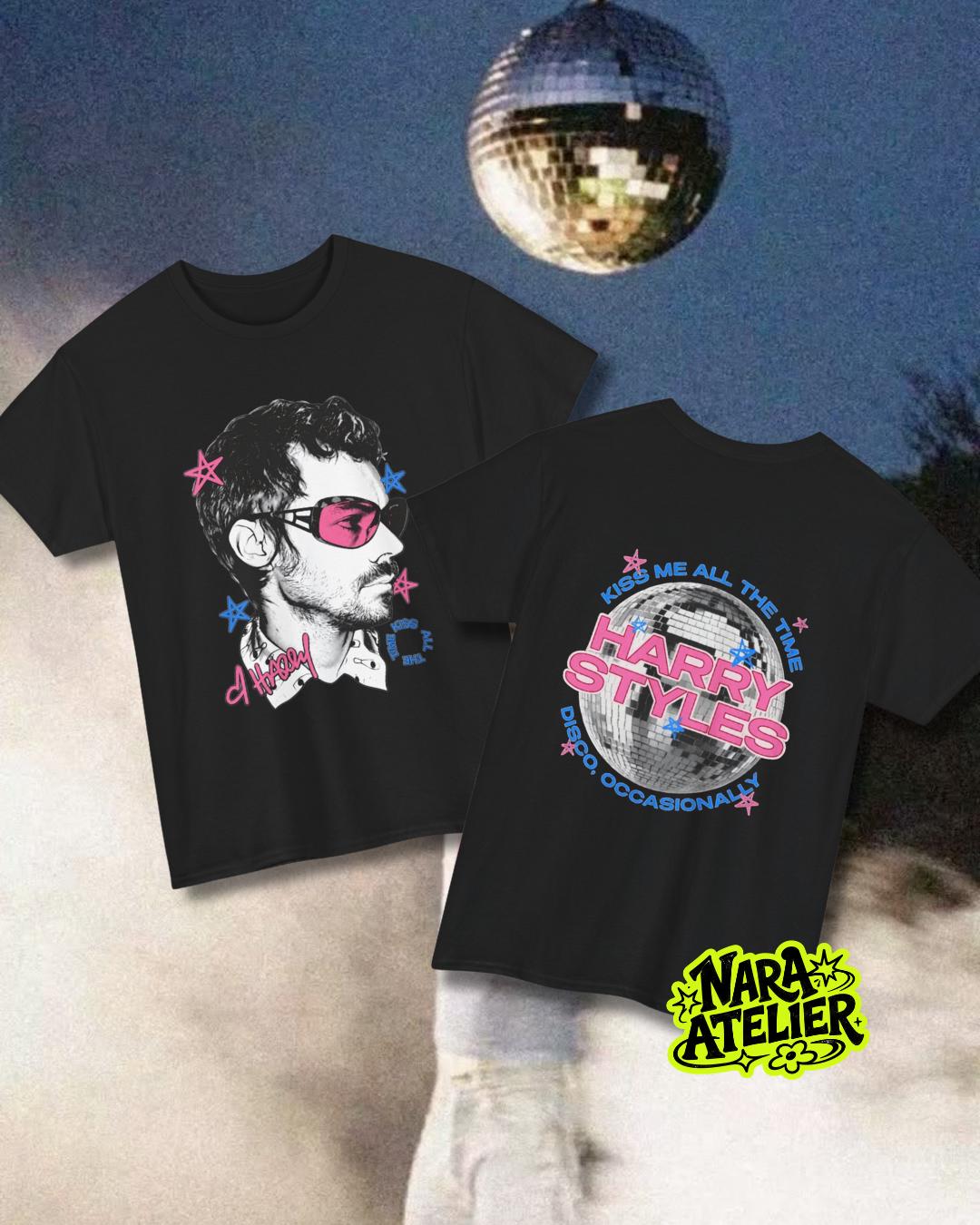 May include: Two black t-shirts featuring graphic prints. One shirt shows a profile illustration of a person wearing pink sunglasses with pink and blue stars. The other shirt displays a disco ball with the text HARRY STYLES, KISS ME ALL THE TIME.