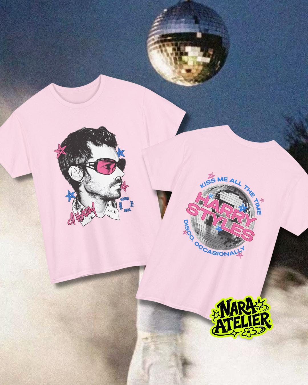 May include: A light pink t-shirt featuring a graphic of a person wearing pink-tinted sunglasses on the front and a disco ball graphic with the text "KISS ME ALL THE TIME HARRY STYLES DISCO OCCASIONALLY" on the back, accented with small blue and pink stars.