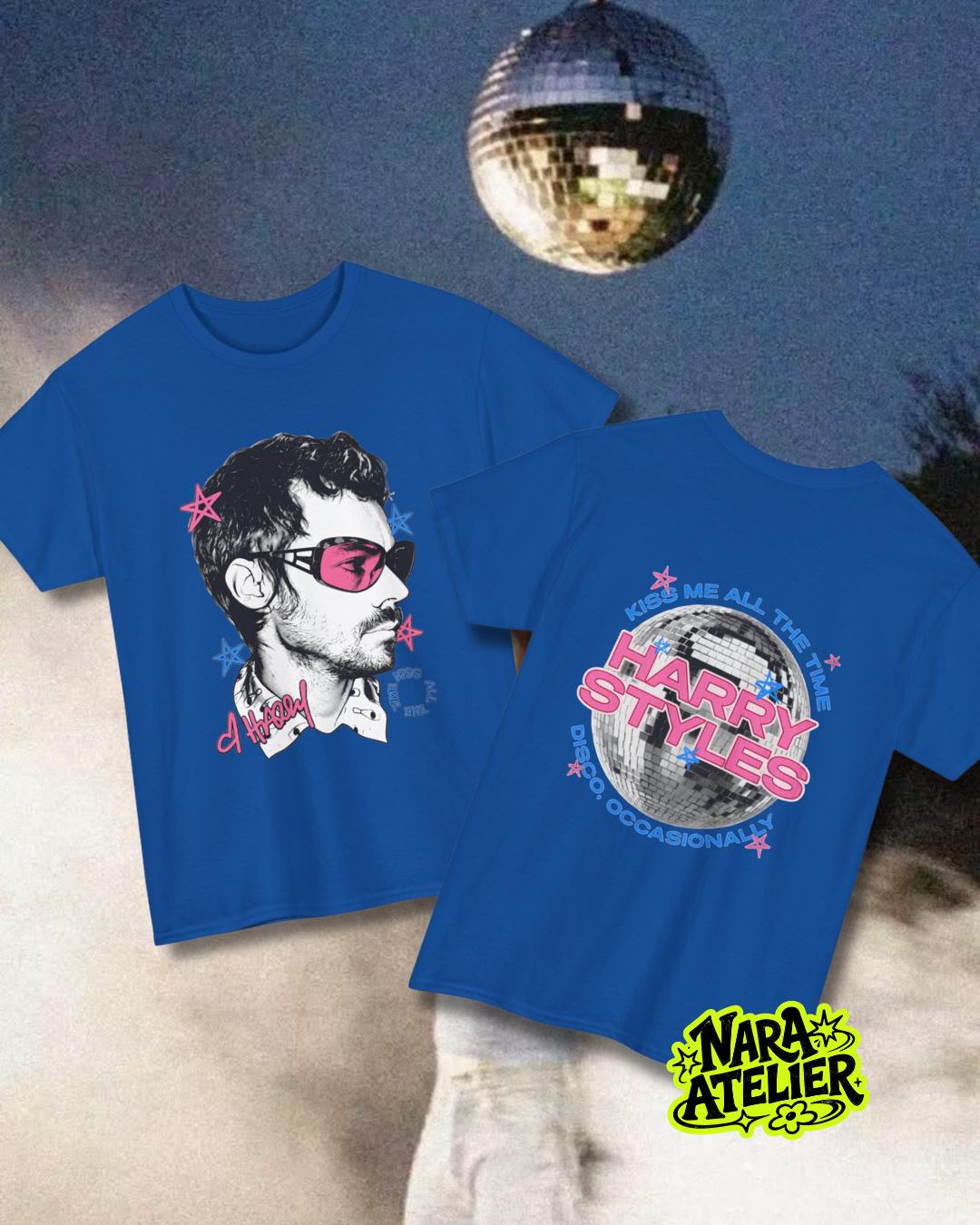 May include: A royal blue t-shirt featuring a graphic of a person wearing pink sunglasses on the front and a disco ball graphic with the text "HARRY STYLES KISS ME ALL THE TIME DISCO, OCCASIONALLY" on the back, accented with pink and blue stars.
