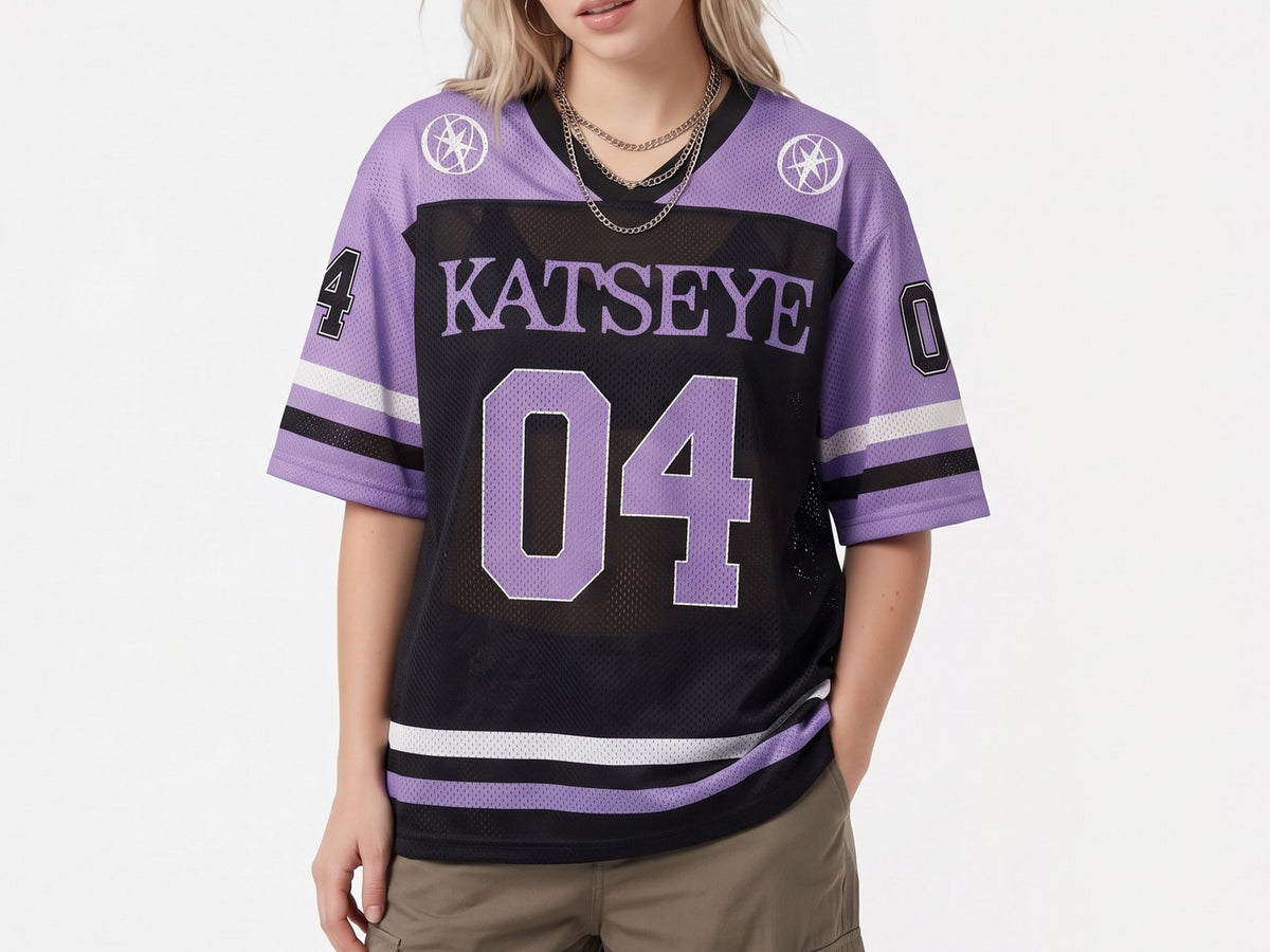 May include: A black and lavender mesh jersey featuring the text KATSEYE and the number 04 in large purple font on the front. The sleeves have the number 04 in black and white, with white and black stripes at the cuffs and hem, and circular star logos.