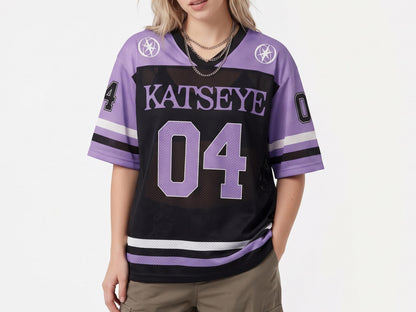 May include: A black and lavender mesh jersey featuring the text KATSEYE and the number 04 in large purple font on the front. The sleeves have the number 04 in black and white, with white and black stripes at the cuffs and hem, and circular star logos.
