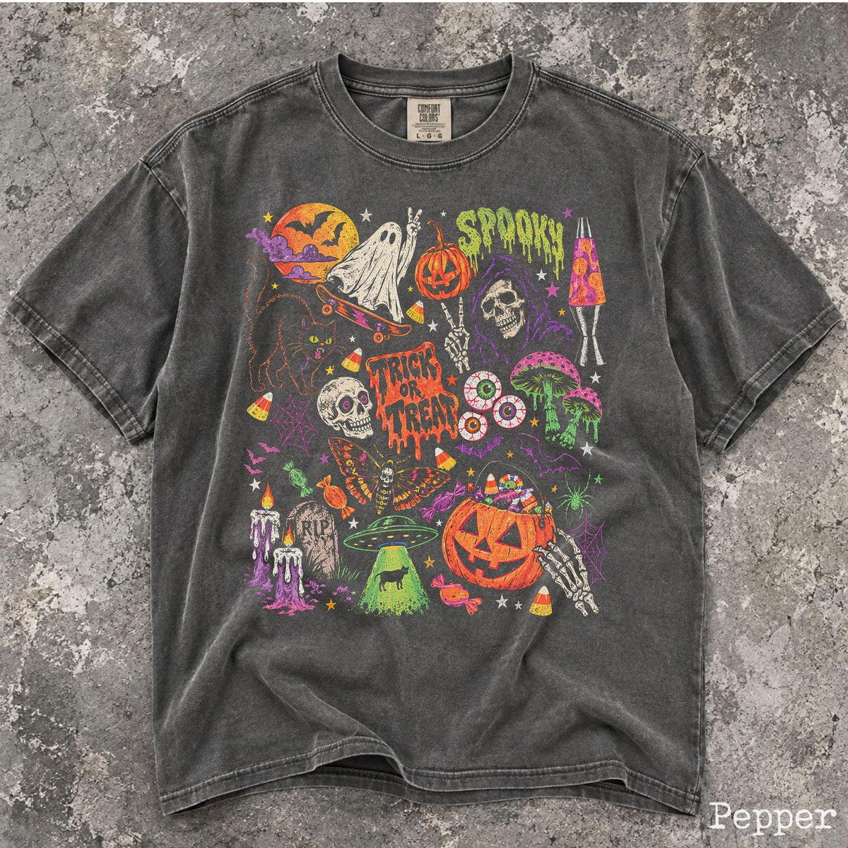 May include: A charcoal gray short-sleeve t-shirt featuring a vibrant Halloween-themed graphic print. The design includes a ghost on a skateboard, a pumpkin, a skull, a lava lamp, mushrooms, a UFO, a jack-o'-lantern bucket, and the text "SPOOKY" and "TRICK OR TREAT."