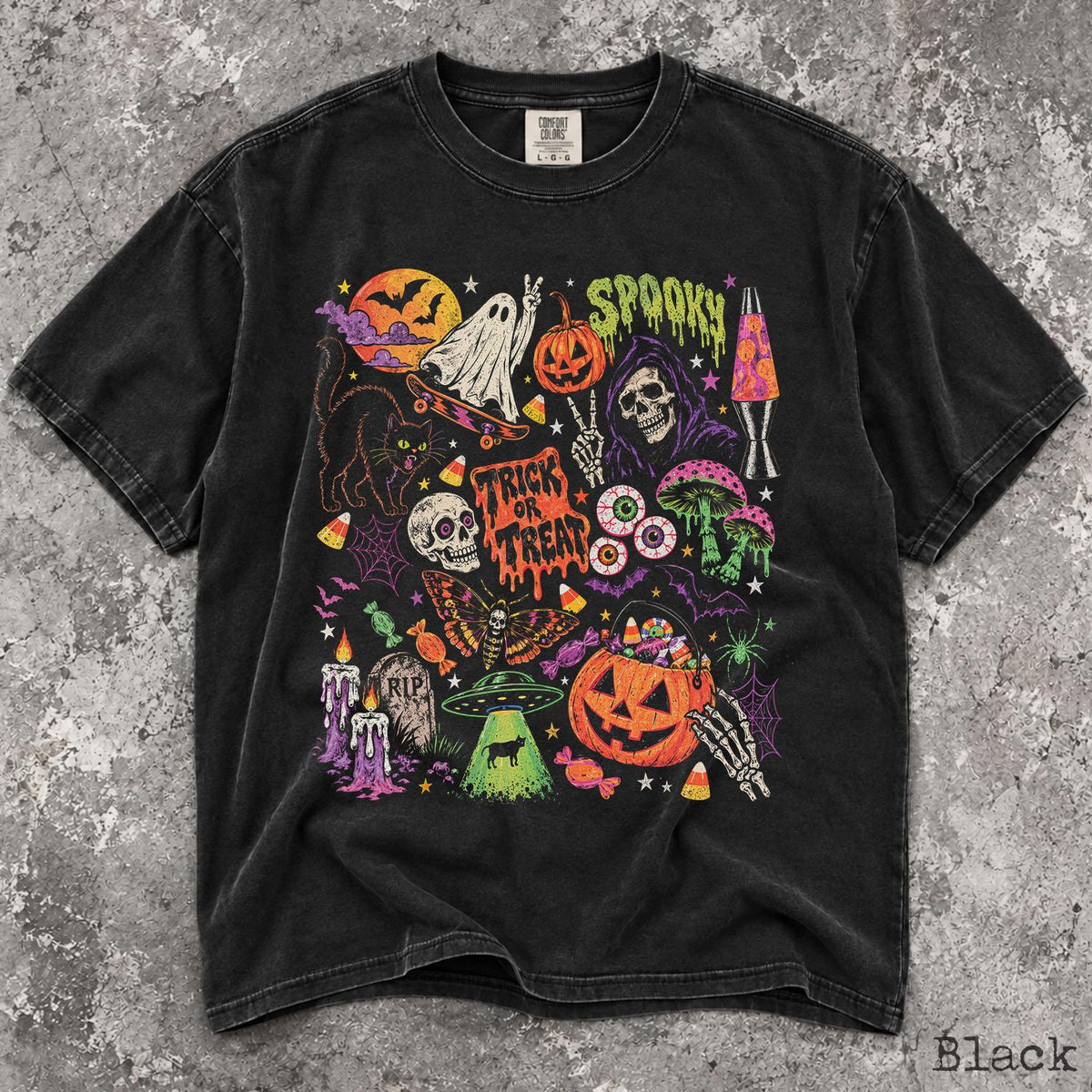 May include: A black short-sleeve t-shirt featuring a colorful graphic print of Halloween-themed illustrations including a ghost on a skateboard, a pumpkin, a skull, a black cat, a moth, a lava lamp, a UFO, and the text "SPOOKY" and "TRICK OR TREAT."