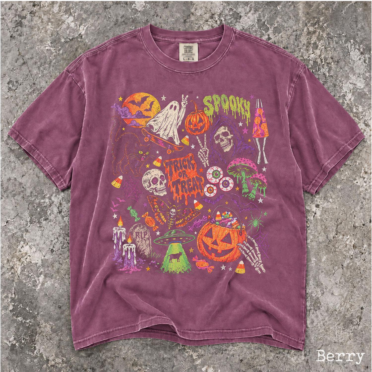 May include: A berry-colored short-sleeve t-shirt featuring a multi-colored graphic print of Halloween-themed illustrations including a ghost on a skateboard, a skull, a pumpkin, mushrooms, a UFO, and the text "SPOOKY" and "TRICK OR TREAT".