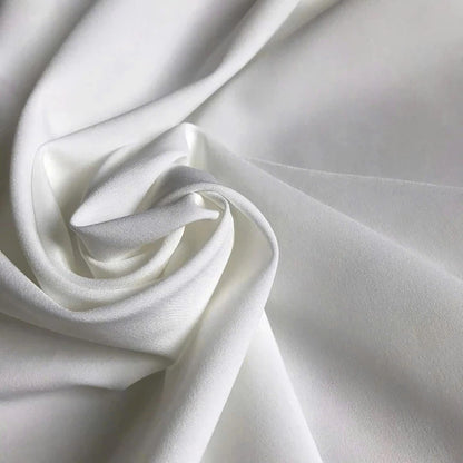 May include: A solid white fabric with a smooth, matte texture, draped in soft, flowing folds that create deep shadows and highlights across the surface. The material appears opaque and consistent in color, showcasing a clean, neutral aesthetic.