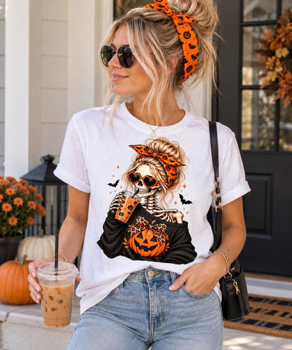 A blonde woman wearing sunglasses, an orange headband, and a white t-shirt featuring a female skeleton graphic holding an iced drink.