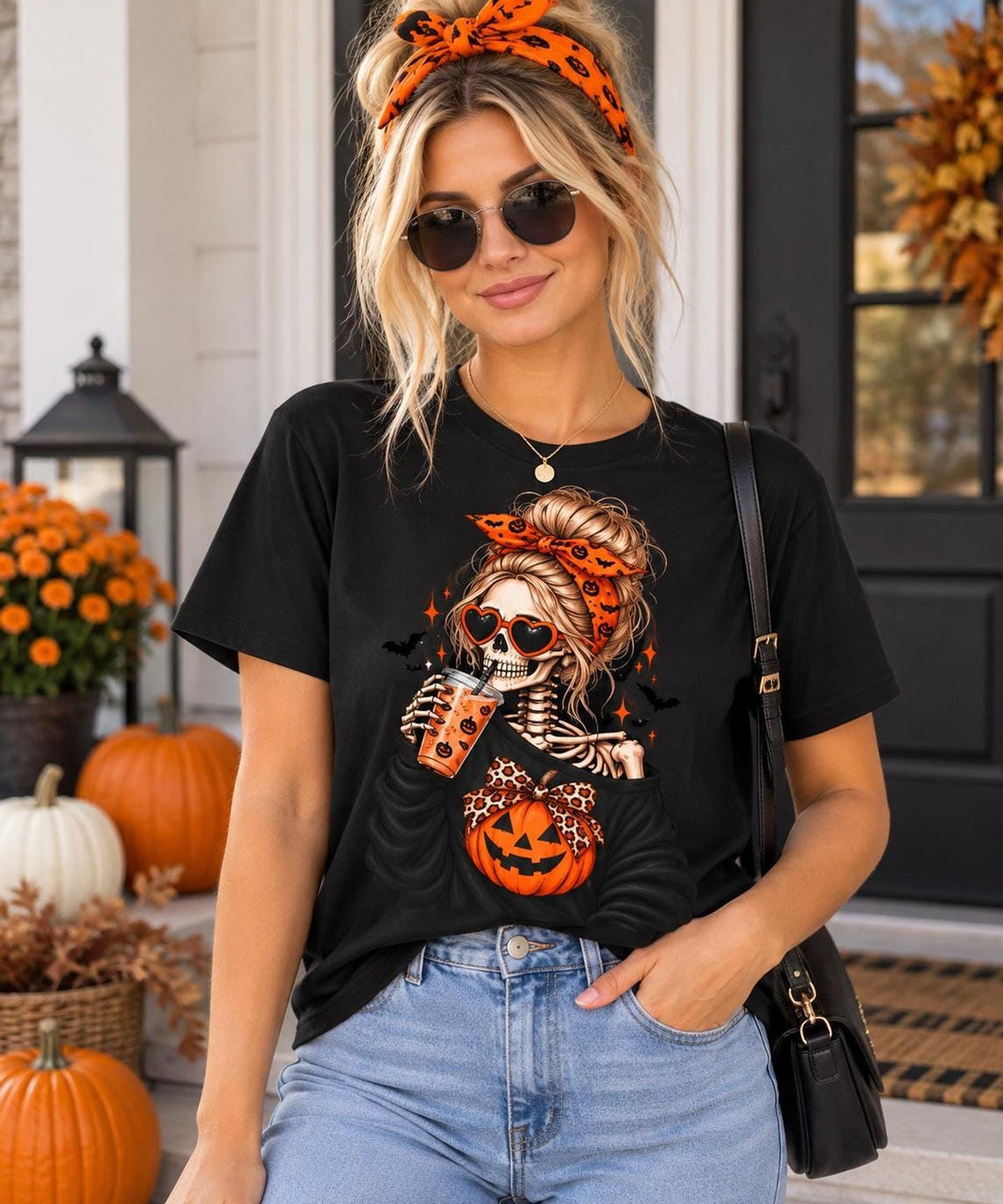 A blonde woman wearing sunglasses, an orange headband, and a black t-shirt featuring a female skeleton graphic holding an iced drink.
