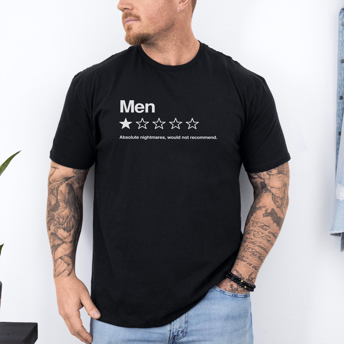 May include: A black short-sleeved t-shirt featuring the white text Men above a single filled-in star and four empty star outlines. Below the stars, the text reads Absolute nightmares, would not recommend. The shirt has a crew neckline.