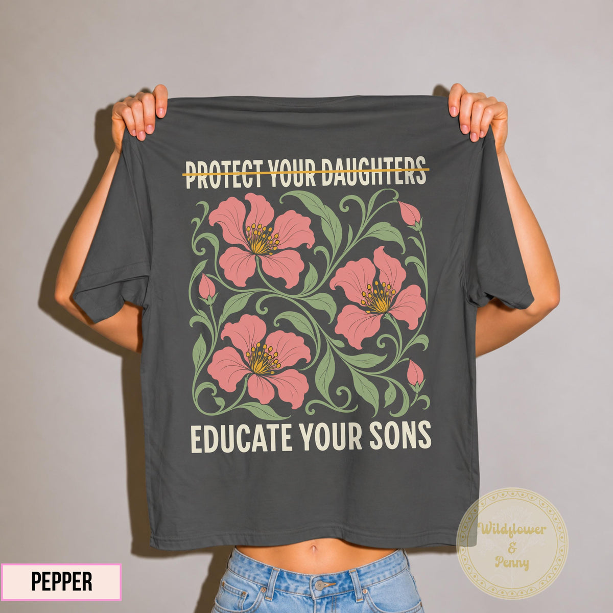 May include: A charcoal gray t-shirt featuring the text PROTECT YOUR DAUGHTERS with a line through it and EDUCATE YOUR SONS in cream lettering. The center graphic displays three large pink flowers with yellow centers surrounded by green leafy vines.