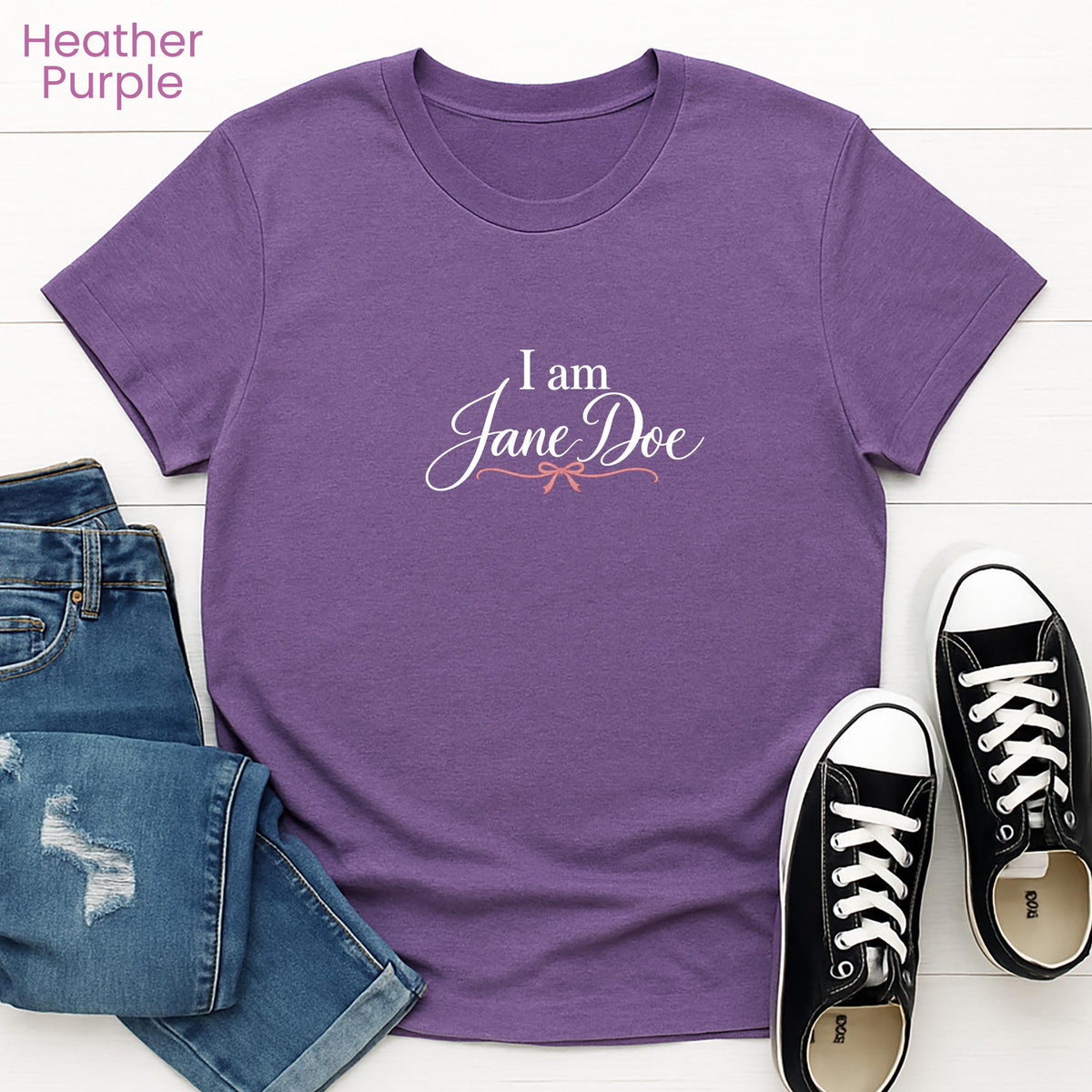 a purple t-shirt with the text "I am Jane Doe" printed on it, along with a pair of blue jeans and black and white sneakers.
